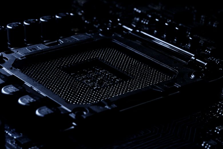 Macro photograph of an empty CPU socket, contact pins visible under raking light.